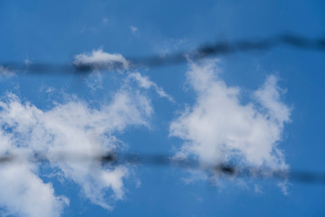 Blur Barbed wire. Barbed wire on fence with blue sky to feel worrying.