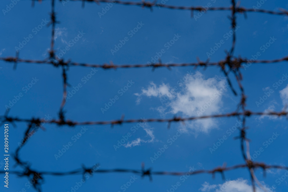 Wall mural barbed wire. barbed wire on fence with blue sky to feel worrying.