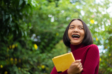 Happy Asian young girl hold notebook with leaf green background.