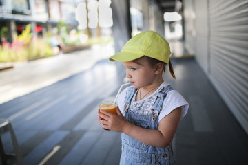 child drinking fresh orange juice through straw