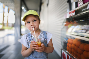 child drinking fresh orange juice through straw