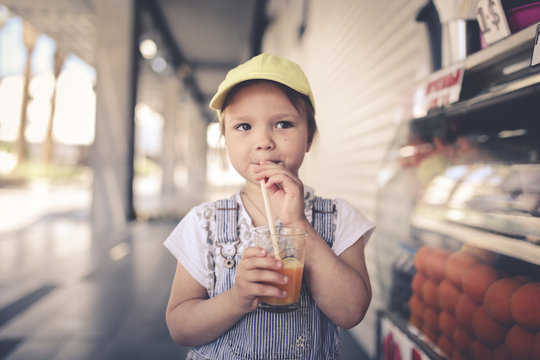 Child Drinking Fresh Orange Juice Through Straw