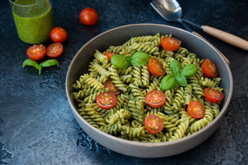 Fusilli pasta with green pesto sauce on a black concrete background. traditional Italian dish.