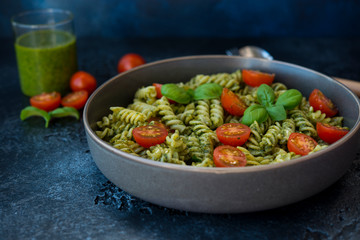 Fusilli pasta with green pesto sauce on a black concrete background. traditional Italian dish.