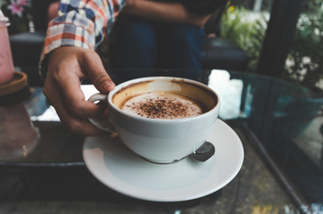 closeup woman drinking modern hot black coffee the cappuccino on dark background with coffee bubble foam pattern and texture in black cup looking and feel so delicious on glasses table in coffee shop.