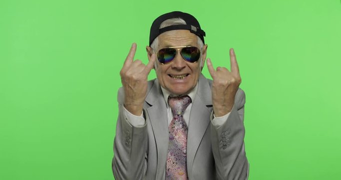 Funny senior businessman in sunglasses show sign of the horns with his hands