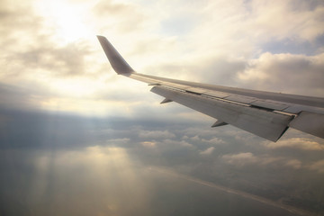 Wing of airplane with rays through clouds