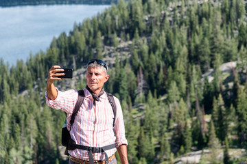 Relaxed man making a selfie on the top of a mountain. Relax and holiday concept