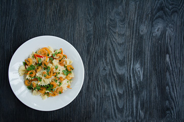 Italian pasta in a sauce with shrimps on a plate, top view. Dark wooden background. Space for text.