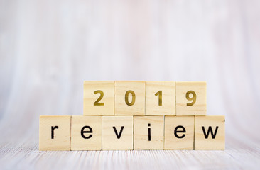 The word review on wooden cube block on white wooden table. 2019 review concept