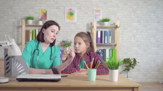 Doctor otolaryngologist explains the hearing impaired teenager about the hearing aid