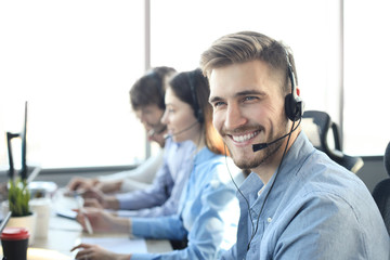 Fototapeta Portrait of call center worker accompanied by his team. Smiling customer support operator at work. obraz