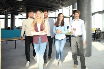 Obraz premium Full length of young people in smart casual wear discussing business and smiling while walking through the office.