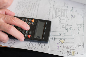 old man doing some math calculations using digital calculator at his work place