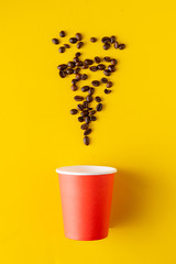 a paper glass for hot drink with coffee beans on color background