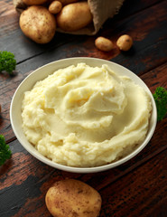 Mashed potatoes in white bowl on wooden rustic table. Healthy food