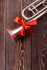 Trumpet with red ribbon on wooden background. Metal trumpet or cornet with red ribbon and copy space. Classical music equipment. © DenisProduction.com