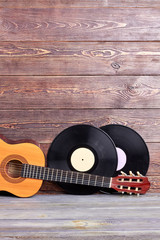 Musical instuments on vintage wooden background. Acoustic guitar and two vinyl records on wooden boards with copy space. Retro music background.