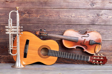 Musical instruments of vintage style. Trumpet, acoustic guitar and violin on wooden background. Classical musical instruments.