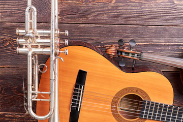 Musical instruments on wooden background. Guitar, trumpet, violin and copy space. Set of professional musical equipment.