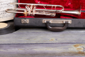 Trumpet in velvet case and copy space. Vintage style musical equipment on wooden background with...