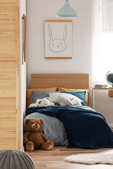 Brown cute teddy bear on wooden floor of stylish bedroom interior for kids