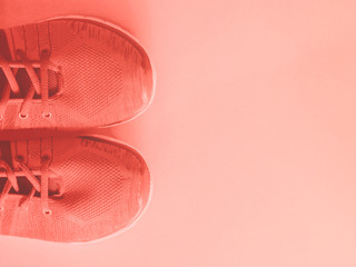 Coral pink trainers on empty background.