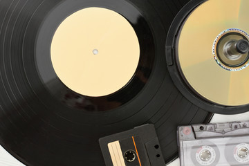 Close up vinyl record, compact disc and cassettes. Detail of vinyl plate, audio cassette tapes and...