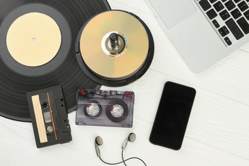 Old and modern musical technology. Vinyl record, compact discs, audio cassettes, earphones, laptop...