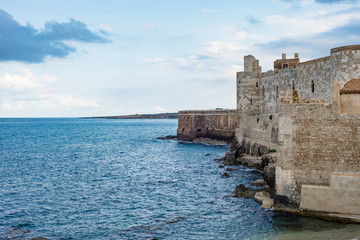 Beautiful view of Maniace castle in Ortigia Syracuse, in front of the sea and sky.