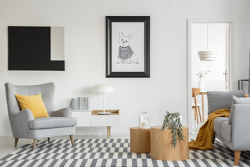 Black and white poster of dog on the wall of fashionable living room interior with two wooden coffee tables with flowers