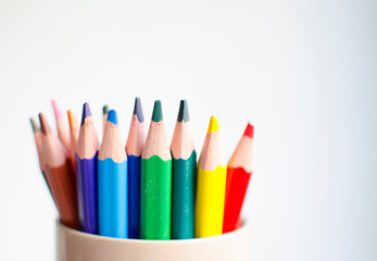 Different colored pencils crayons laying on a wooden board