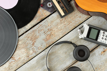 Old and modern audio devices. Wooden background with vinyl lp records, audio cassettes, acoustic...