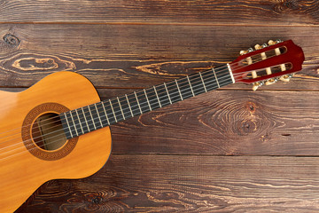 Guitar on brown textured wood. Acoustic guitar on wooden table with text space. Instrument of folk music.