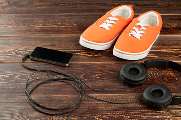 Set for sport activities on wooden background. Headphones, smartphone and sport shoes. Sport and fitness concept.