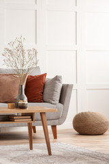 Wooden furniture and grey scandinavian sofa with pillows in beautiful living room interior