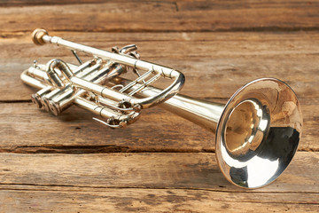 Rusty trumpet on old wooden surface. Antique trumpet on rustic boards. Classical jazzy instrument.