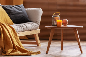 Orange candle on wooden coffee table in cozy living room interior