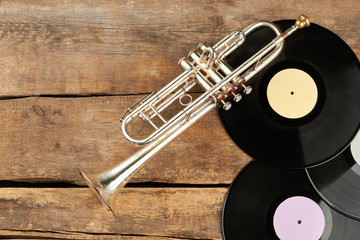 Musical equipment on old wooden surface. Trumpet, vinyl records and copy space. Vintage music...