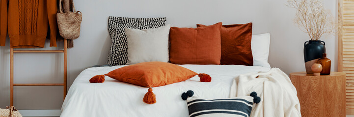 Decorative pillows on a bed in a scandi bedroom interior. Real photo