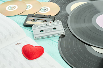 Outdated musical objects close up. Vinyl records, audio cassettes, compact discs, musical notes....