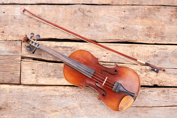 Old violin and fiddle stick. Vintage violin on rustic wooden boards. Musical instrument of orchestra.