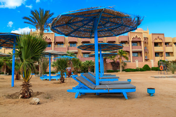 Sun umbrellas and chaise lounges on tropical beach. Concept of rest, relaxation, holidays, resort