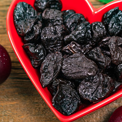 Dried Plums Pitted Prunes in Heart Shaped Bowl Background. Selective focus.