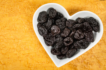 Dried Plums Pitted Prunes in Heart Shaped Bowl Background. Selective focus.