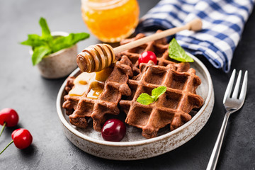 Belgian waffles with honey and berries served on trendy plate. Closeup view. Tasty breakfast or dessert