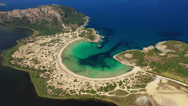 Aerial drone video of semicircular sandy beach and lagoon of Voidokilia, one of the most iconic beaches in Mediterranean sea, with crystal clear turquoise sea, Messinia, Greece