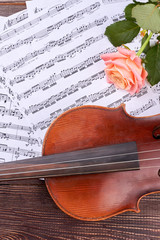 Vintage violin, rose and musical notes. Rose, violin and musical pages on wooden table. Romantic...