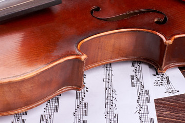 Close up brown violin and musical notes. Detail of violin waist. Instrument of classical music.
