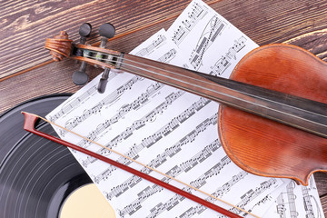 Violin, music notes and vinyl record. Classical music equipment on wooden background.